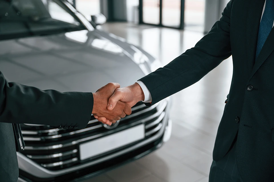 Strângere de mână între client și reprezentant leasing în fața mașinii, la finalul contractului